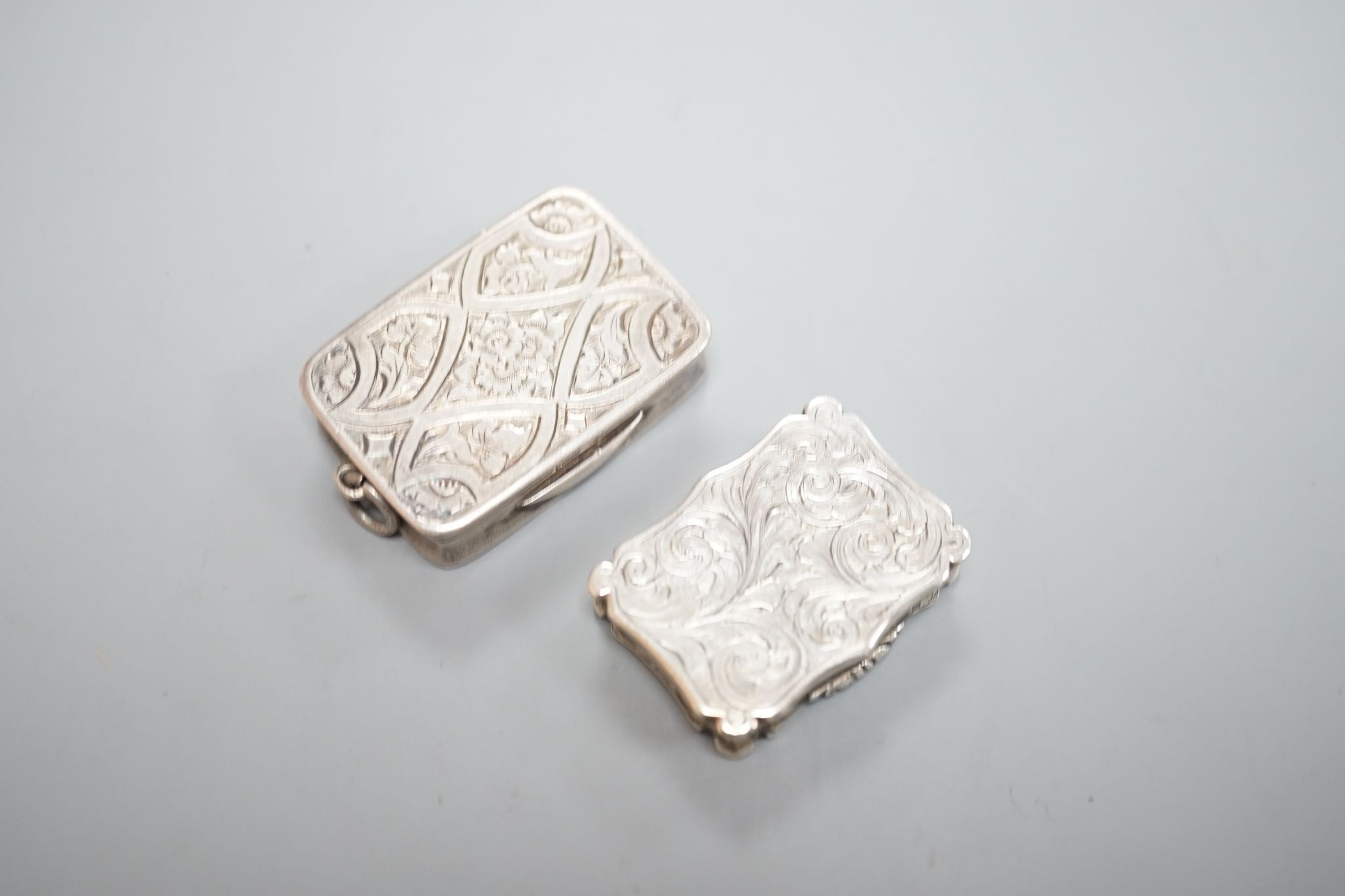 An early Victorian engraved silver shaped rectangular vinaigrette, by Nathaniel Mills, Birmingham, 1844, 31mm and a later silver vinaigrette by George Unite.